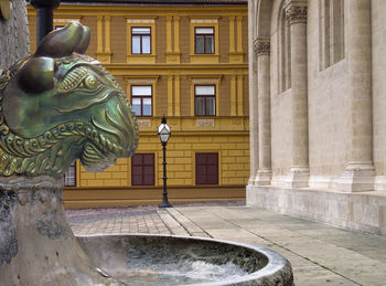 Statue by fountain against building in city