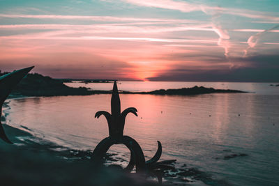 Silhouette tree on beach against sky during sunset