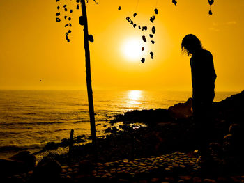 Silhouette woman on beach against sky during sunset