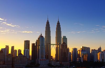 Low angle view of petronas towers and cityscape and against sky during sunset