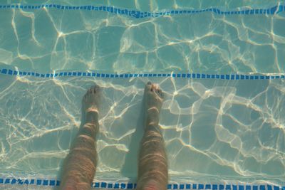 Low section of man standing in swimming pool