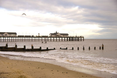 Pier on beach against sky during sunset
