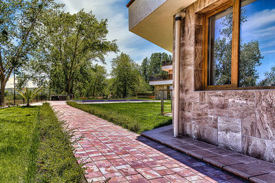 Footpath amidst trees and houses against sky