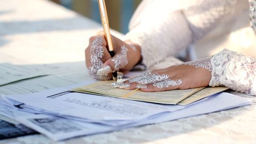 Midsection of woman holding paper with text on table