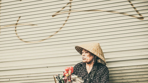 Woman looking away while standing against wall