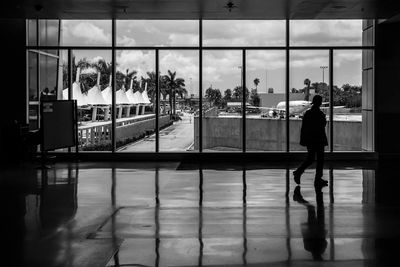 Reflection of woman on glass window against sky