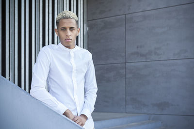 Portrait of young man standing against wall