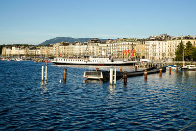 Boats moored at harbor against clear blue sky