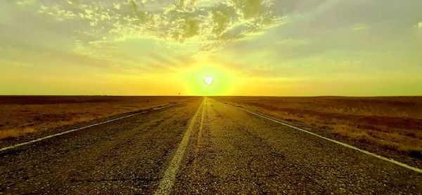 Road amidst land against sky during sunset