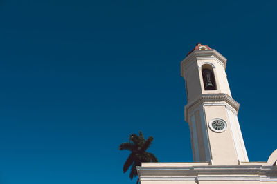 Low angle view of clock tower and building against clear blue sky