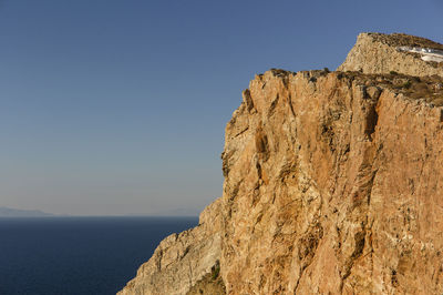 Rock formations by sea against clear blue sky, folegandros , greece