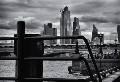 Buildings by river against sky in city