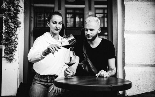 Young woman pouring wine in glass at cafe