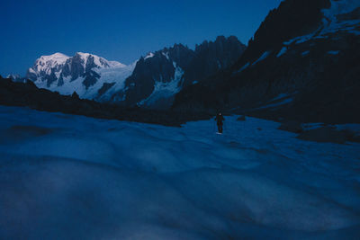 Hiker walking against snowcapped mountain