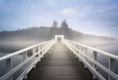 Footbridge along trees on snow covered landscape