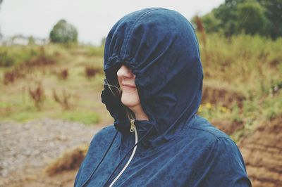 Close-up of woman wearing raincoat while standing on field during rain