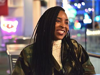 Portrait of smiling young woman standing in city at night