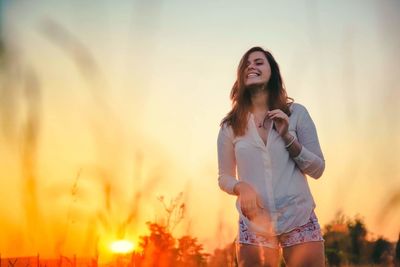 Portrait of a smiling young woman in field during sunset