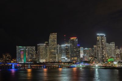 Illuminated modern buildings in city against sky at night