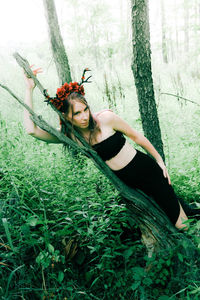 Portrait of young woman lying on tree trunk