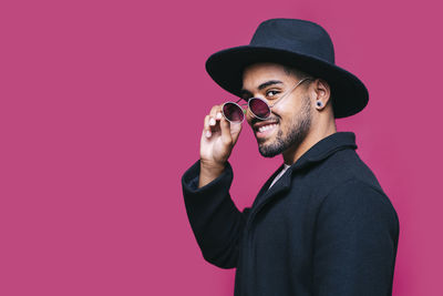 Man holding camera while standing against wall against red background