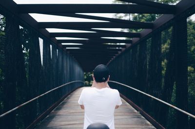 Rear view of man walking on footbridge