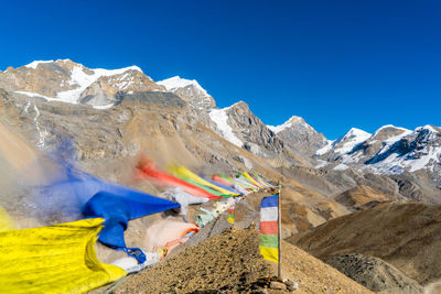 Flags flying by mountains against clear blue sky