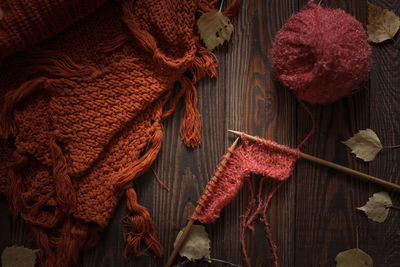 Cozy autumn background with knitted sweater scarf and ball with knitting wood needles, 
