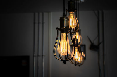 Close-up of illuminated light bulb hanging on wall at home