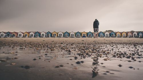 Surface level view of man standing at beach against huts