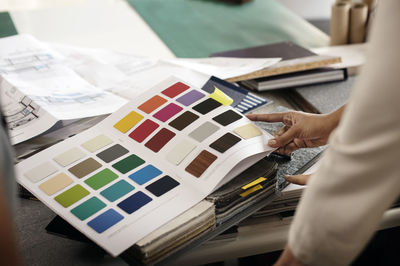 Cropped image of interior designer examining color swatches at office