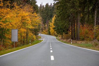 Road amidst trees in forest during autumn