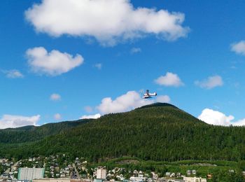 Airplane flying over mountain against sky