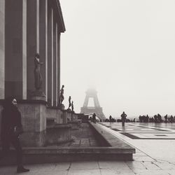 Historic building in city against eiffel tower during foggy weather