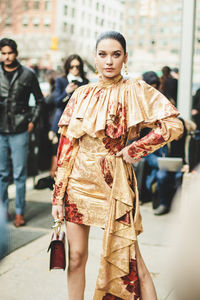 Portrait of young woman standing on street in city