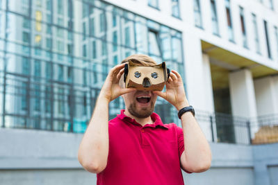 Man wearing virtual reality headset while standing against built structure