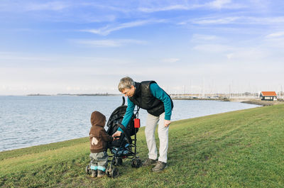 Grandfather and granddaughter at beach against sky