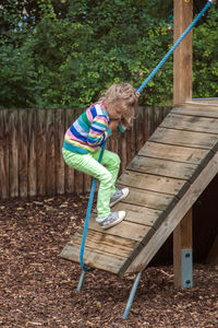 Girl climbing with rope on outdoor play equipment