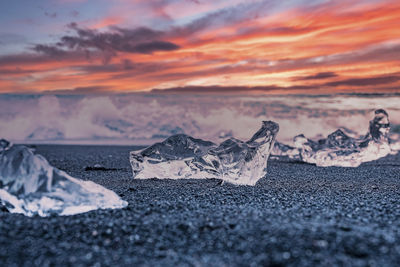 Iceberg chunk on black sand at diamond beach against dramatic sky during sunset