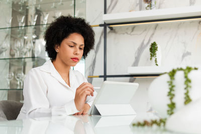 Woman looking at camera while sitting on table