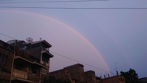Low angle view of rainbow over buildings against sky