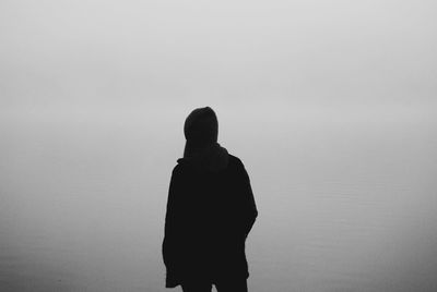 Rear view of person by lake during foggy weather