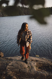 Smiling woman looking away against lake in forest