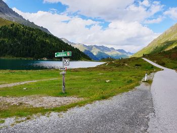 Road sign by mountain against sky