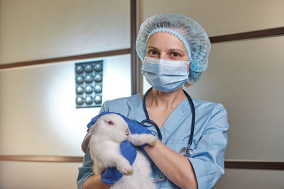 Portrait of veterinarian holding rabbit