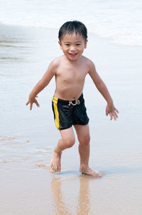 Portrait of happy boy on beach against sky