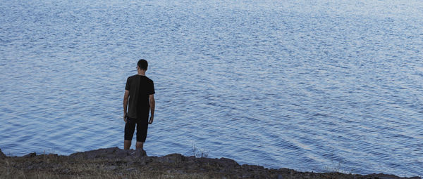 Rear view of man standing by sea