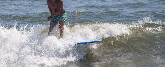Man catching a wave surfing on a blue surfboard at gilgo beach on long island in new york.