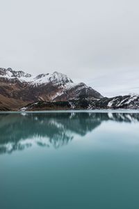 Scenic view of lake by snowcapped mountains against sky