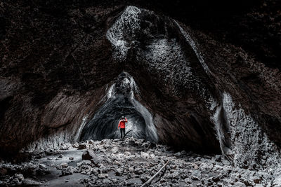 Rear view of person standing in cave